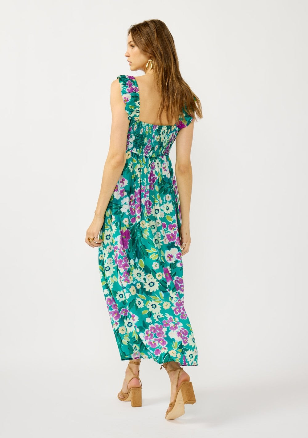 woman wearing a floral maxi dress in teal with ruffled straps and a smocked back, styled with block heel sandals
