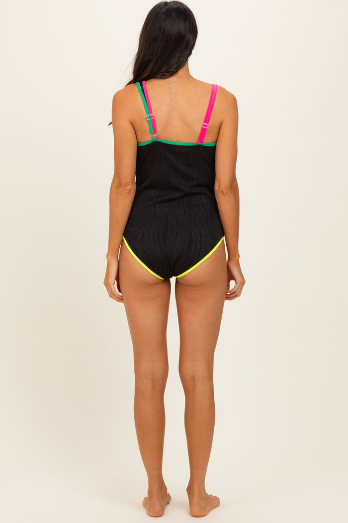 woman wearing a black ribbed swimsuit with colorful straps and a low-cut back