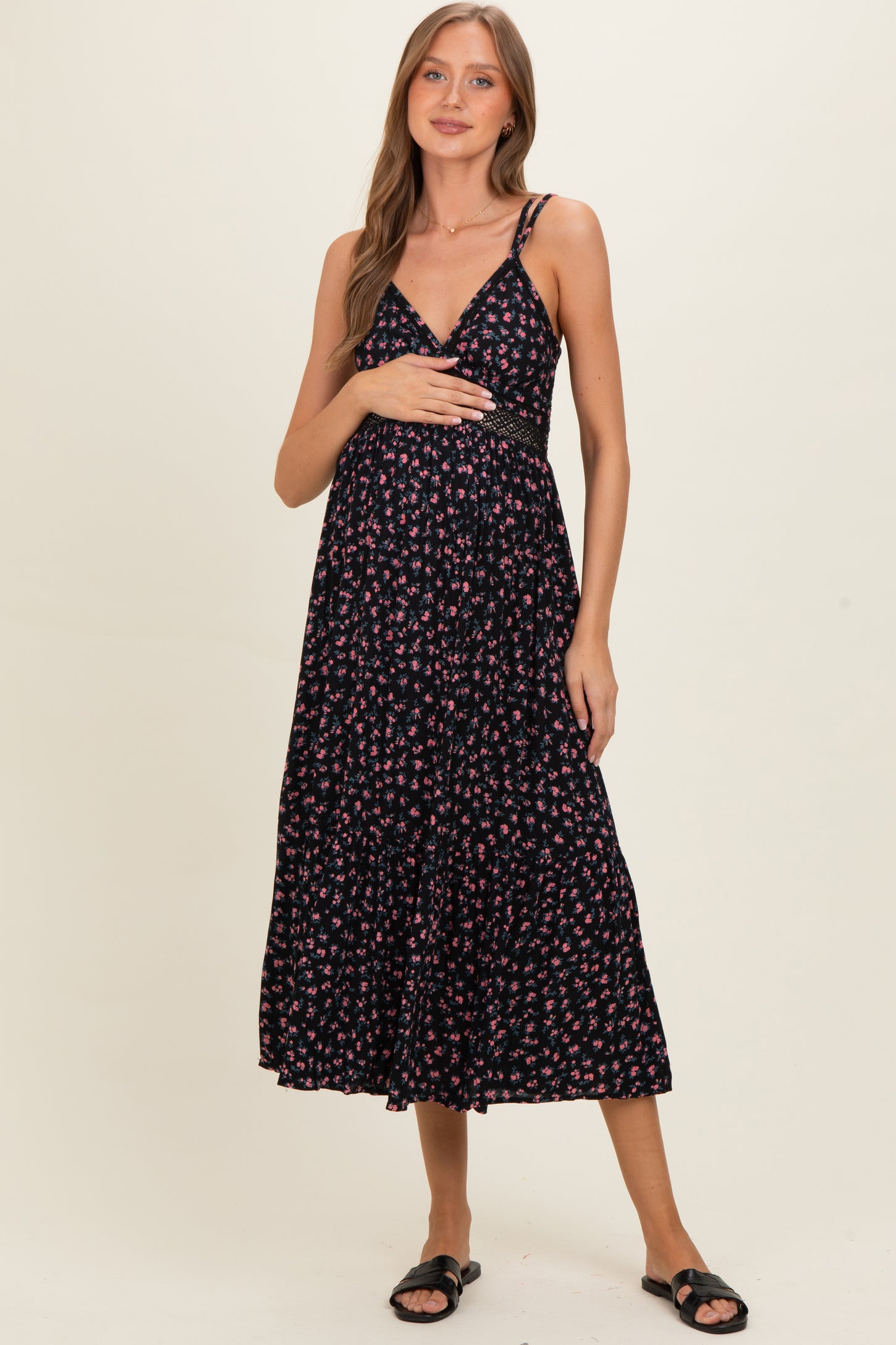 woman wearing a black floral maternity maxi dress and holding her baby bump