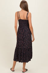 woman wearing a black floral maternity maxi dress with a smocked bodice and tiered ruffle hem, showing her back