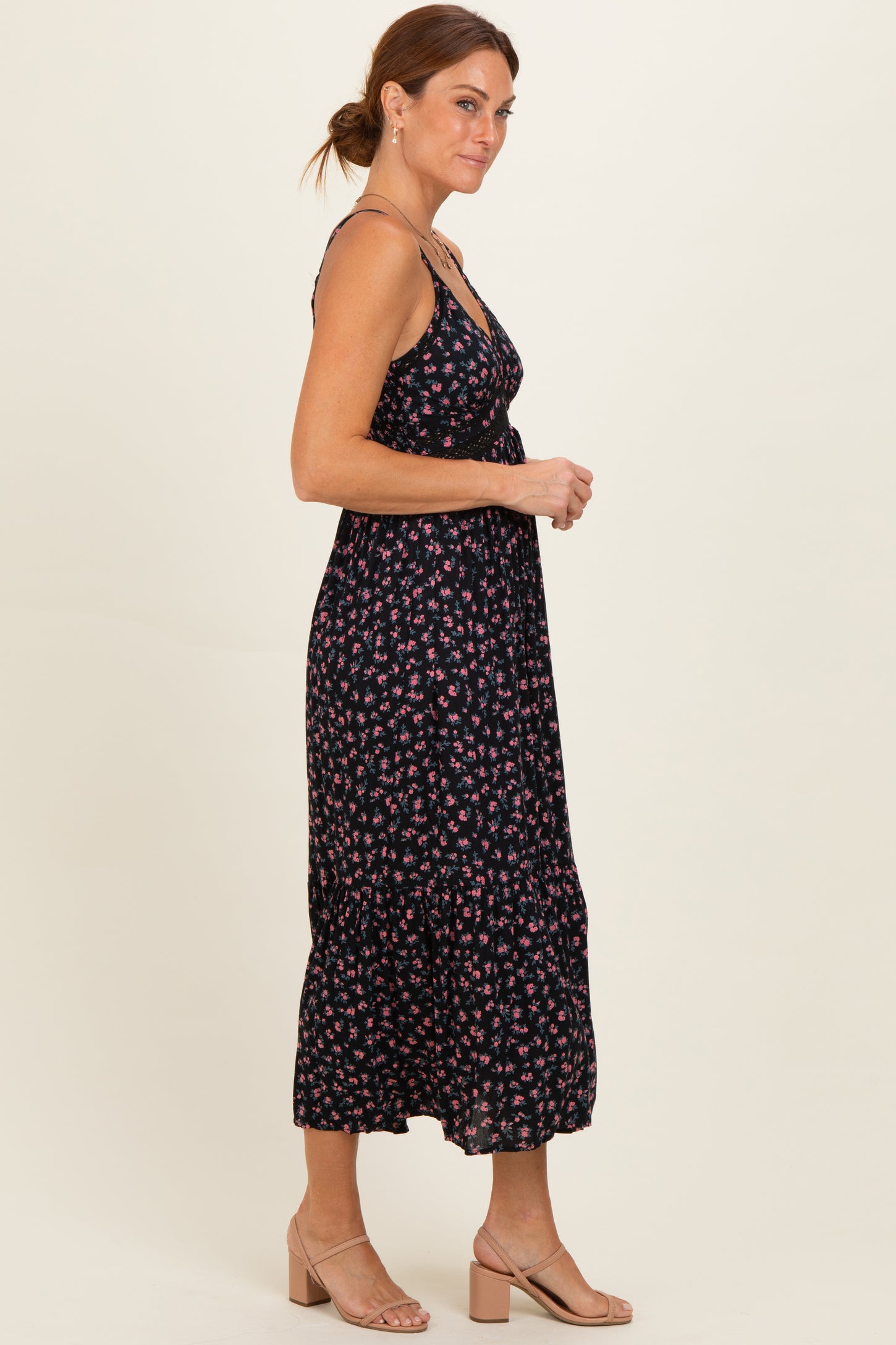 woman wearing a black floral midi dress with spaghetti straps and a tiered skirt