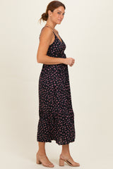 woman wearing a black floral midi dress with spaghetti straps and a tiered skirt