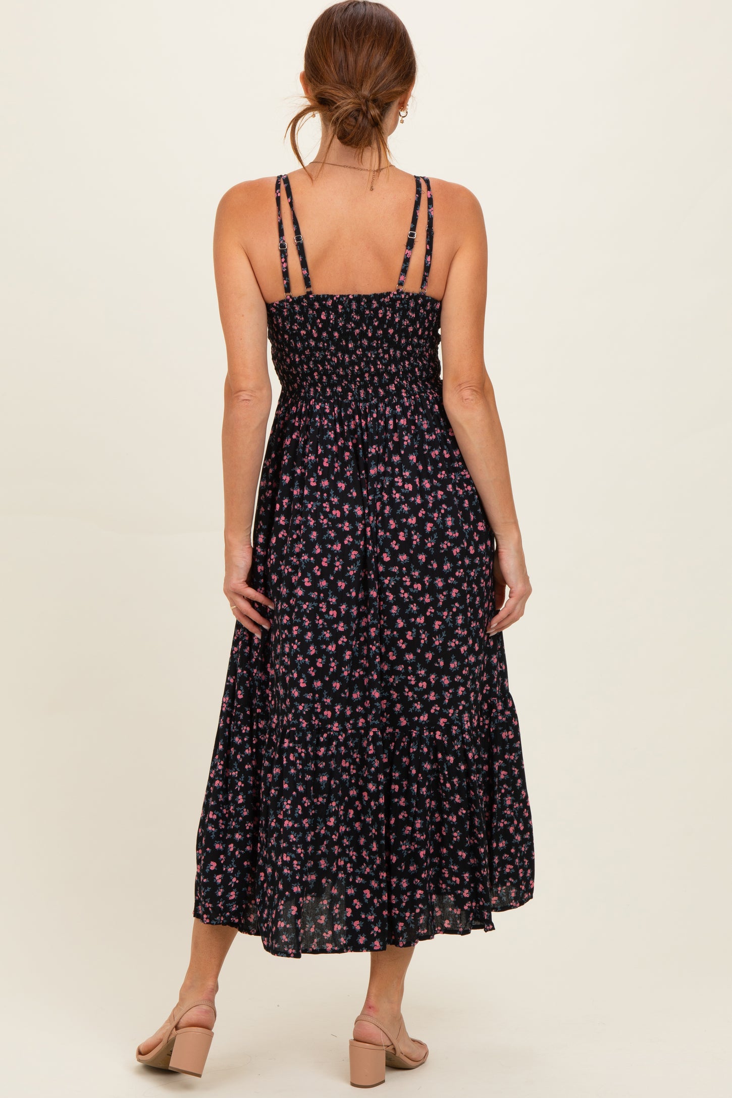 woman wearing a black floral maxi dress with a smocked bodice and adjustable straps, viewed from the back