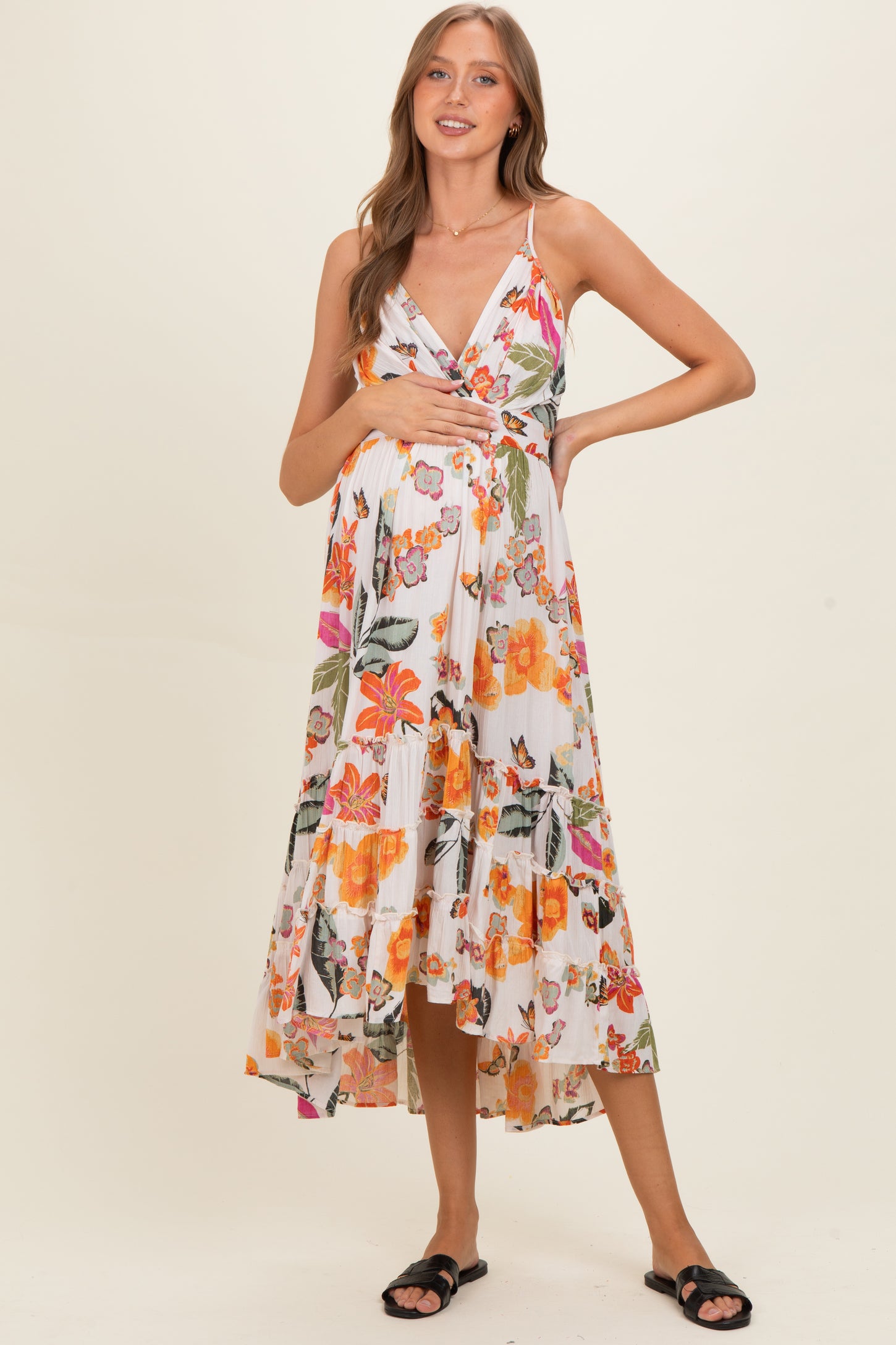 woman wearing a floral maternity maxi dress with a tiered skirt and holding her baby bump