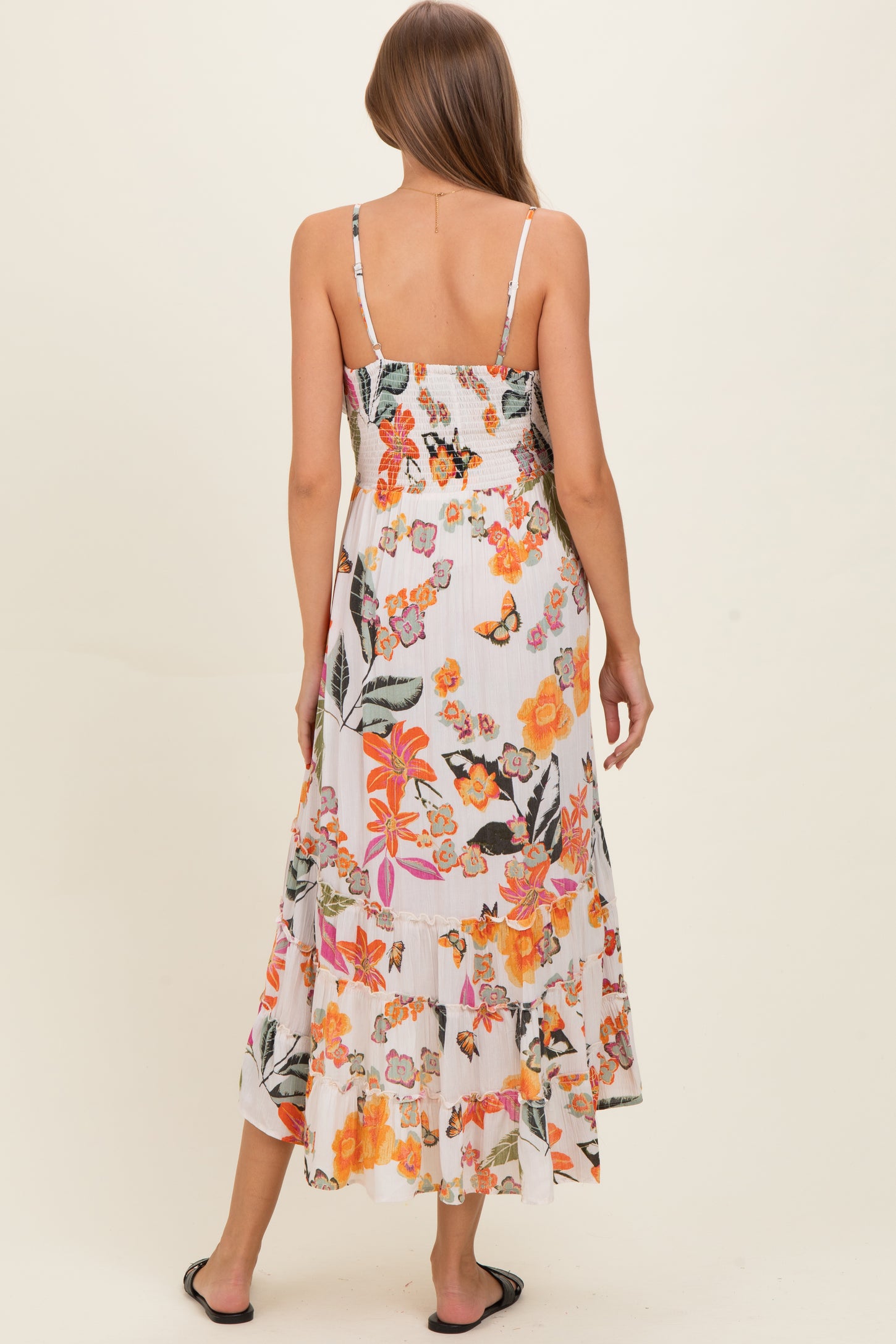 woman wearing a floral print maternity maxi dress with a smocked back and tiered hem, standing from the back