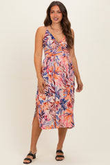 woman wearing a floral print maternity dress with cut-out details and a flowing midi length, showcasing her baby bump