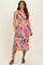 woman wearing a floral print maternity dress with cut-out details and a flowing midi length, showcasing her baby bump