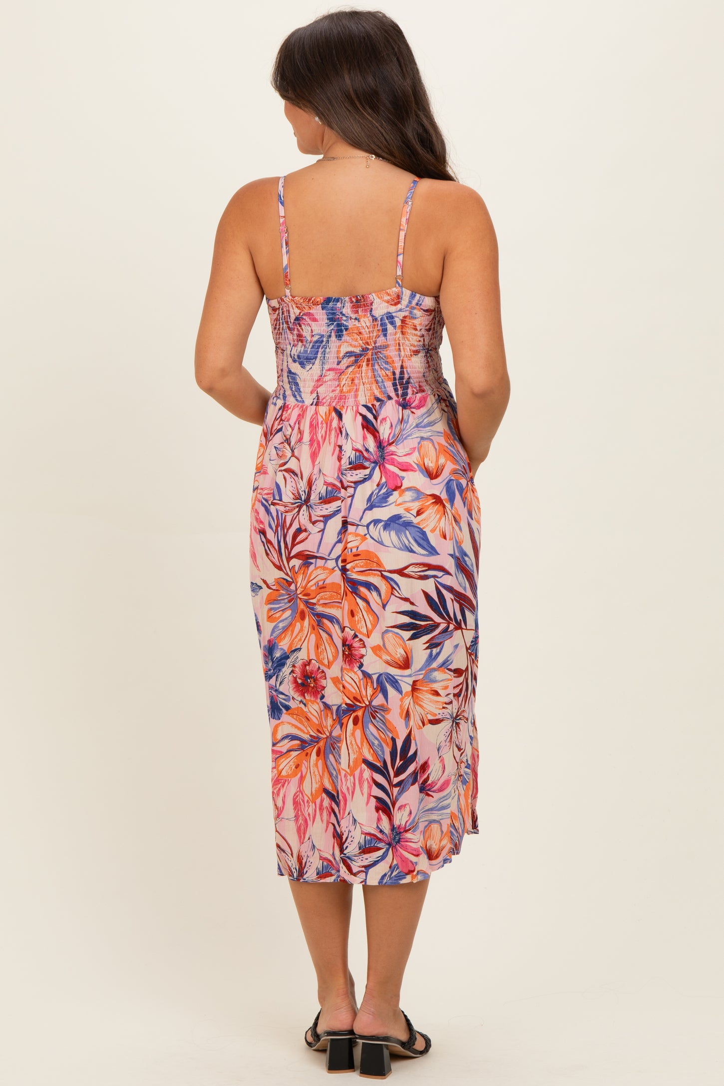 woman wearing a floral print maternity maxi dress with a smocked bodice and spaghetti straps, viewed from the back
