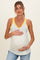 woman wearing a white maternity tank top with yellow floral print and yellow trim, holding her baby bump