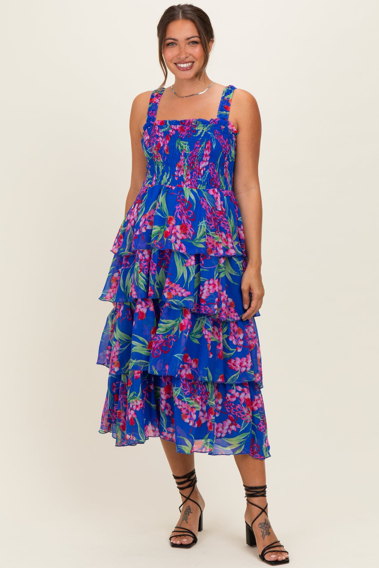woman wearing a blue floral tiered maternity dress with spaghetti straps and a square neckline