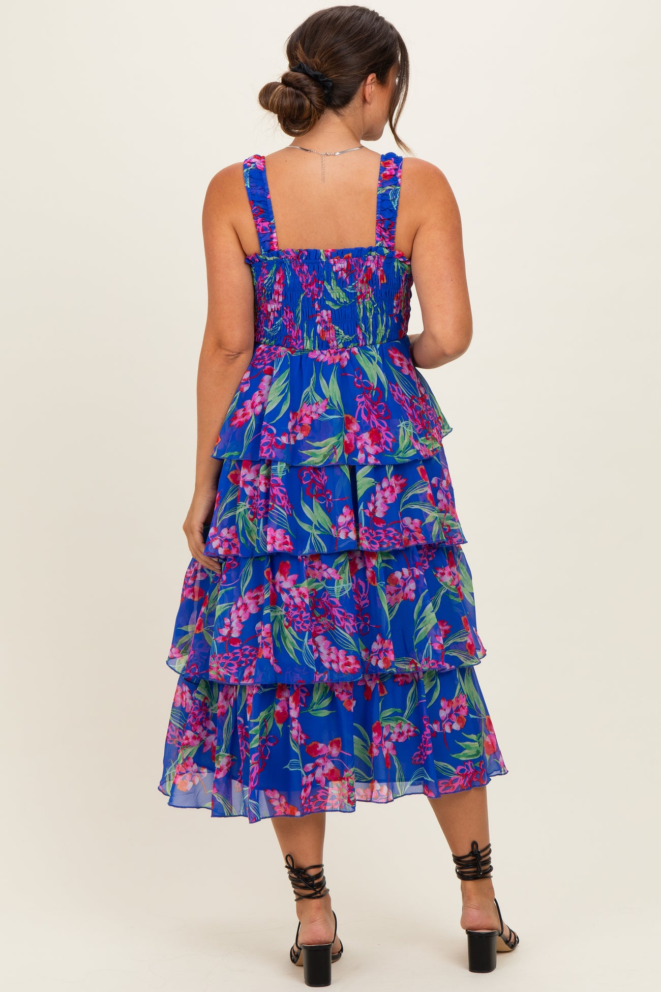 woman wearing a blue floral tiered maternity dress, showing the back with smocked bodice and ruffled layers