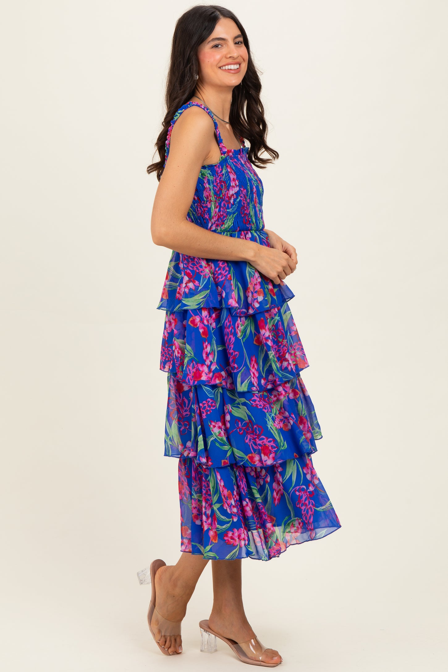 woman wearing a vibrant blue tiered floral dress with spaghetti straps and a flowy silhouette