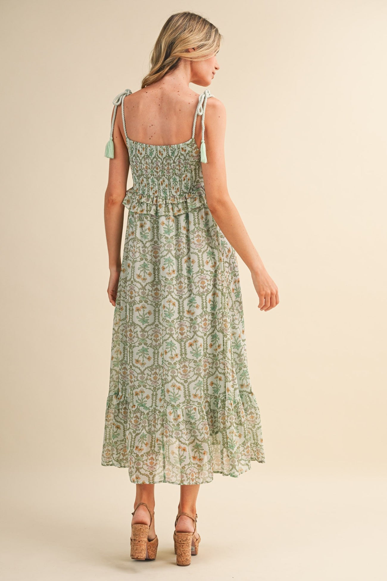 woman wearing a green floral maxi dress with tie straps and a smocked back detail
