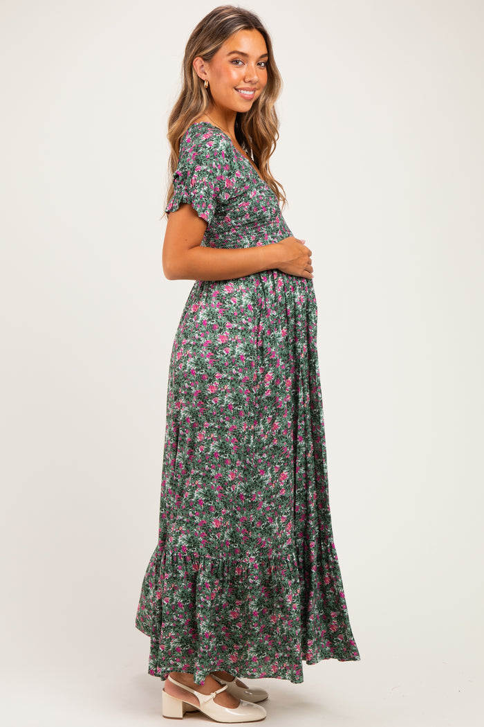 woman wearing a green floral maternity maxi dress and holding her baby bump