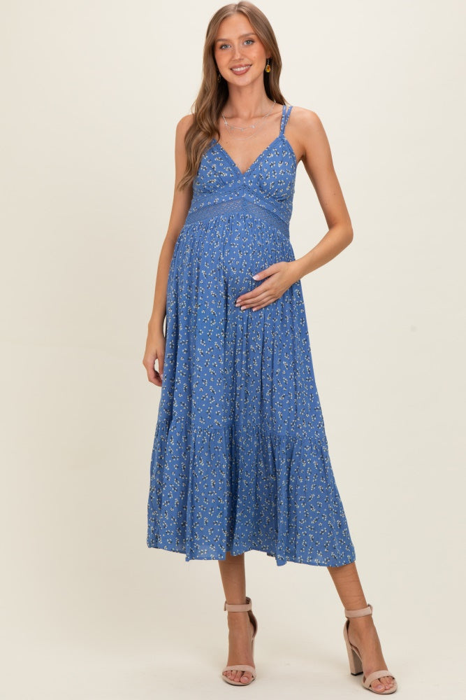 woman wearing a blue floral maternity maxi dress and holding her baby bump