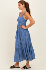 woman wearing a blue floral maxi dress with adjustable straps and a tiered hem, styled with black sandals