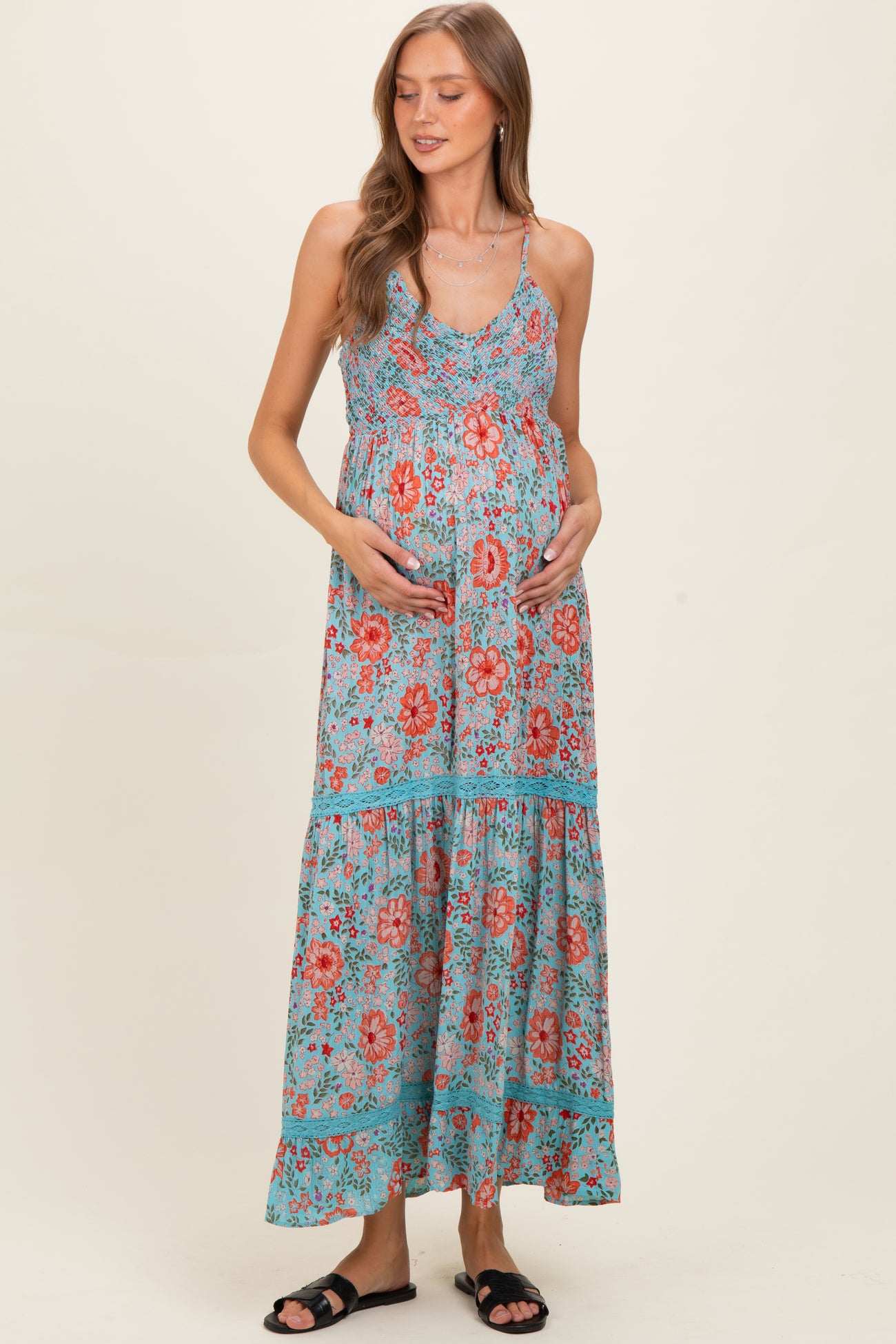 woman wearing a floral print maternity maxi dress with a tiered skirt and holding her baby bump