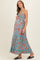 woman wearing a teal floral maxi dress, showing her baby bump, with a tiered skirt and spaghetti straps in maternity wear