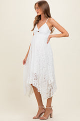 woman wearing a white lace maternity dress with a high-low hemline and spaghetti straps, showing her baby bump