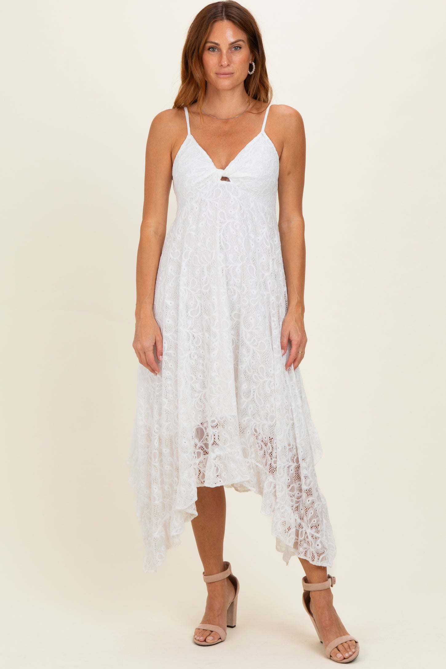 woman wearing a white lace midi dress with a v-neck and asymmetrical hemline, standing on a neutral background