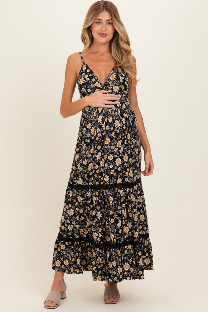 woman wearing a black floral maternity maxi dress with adjustable straps and tiered skirt, showing her baby bump
