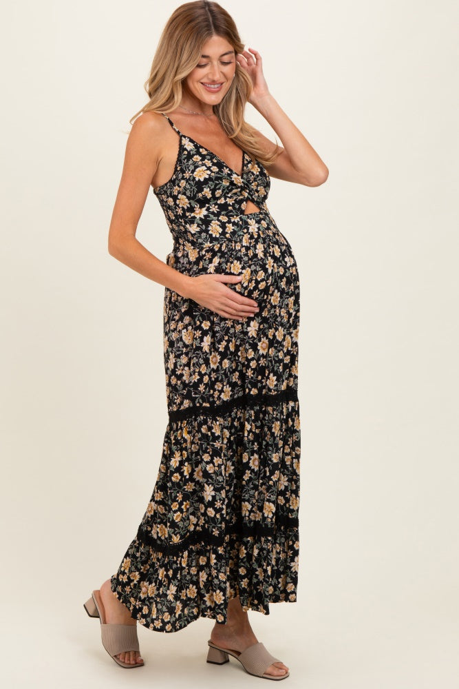 woman wearing a black floral maternity maxi dress and holding her baby bump