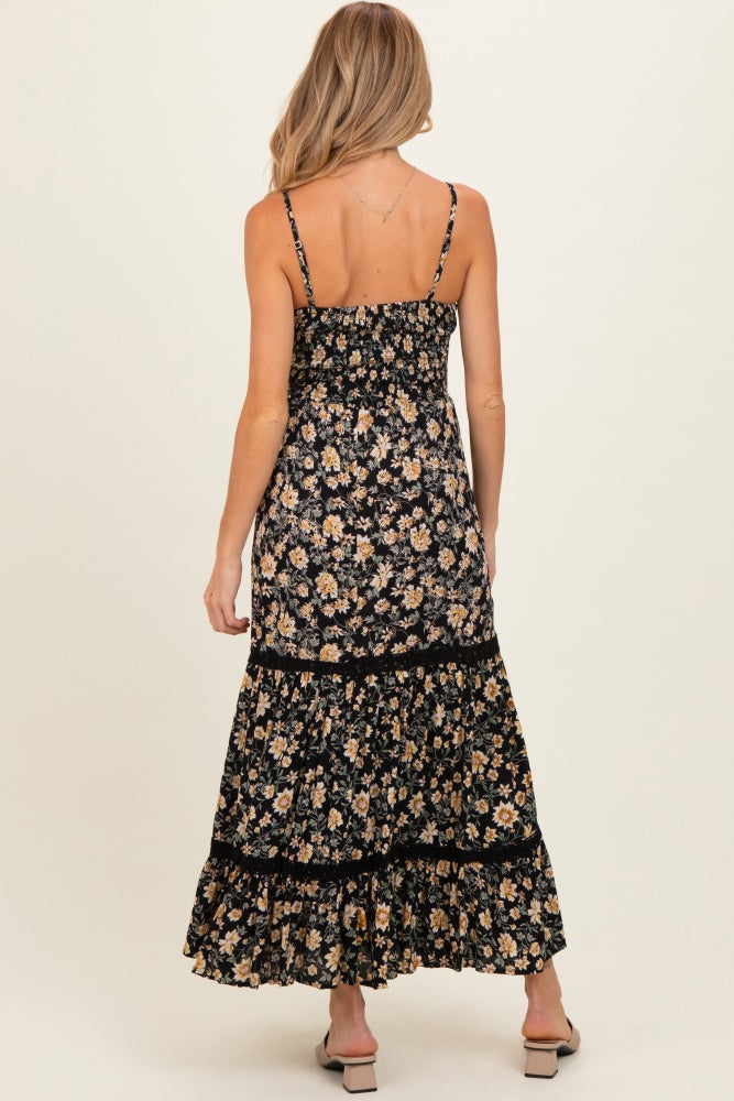 woman wearing a black floral maternity maxi dress with a smocked bodice and tiered skirt, showing her back