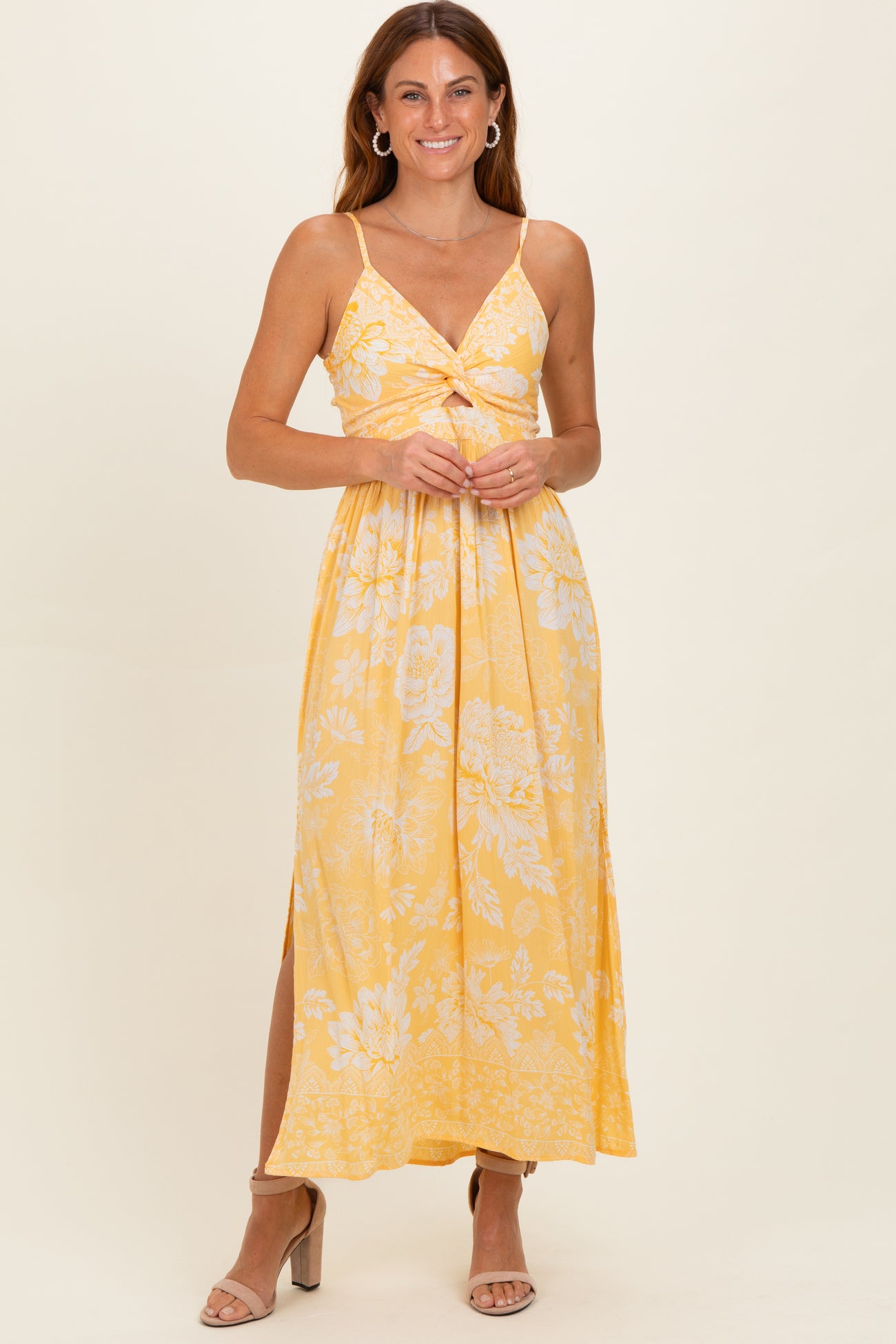 woman wearing a yellow floral maxi dress with a knotted front and side slits, smiling against a neutral background