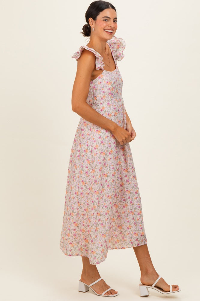 woman wearing a floral midi dress with ruffle straps and smiling, styled with white block-heeled sandals