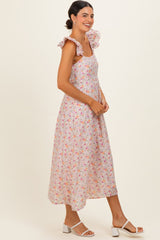 woman wearing a floral midi dress with ruffle straps and smiling, styled with white block-heeled sandals