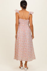 woman wearing a floral maxi dress with ruffled straps and a smocked back detail, viewed from the back