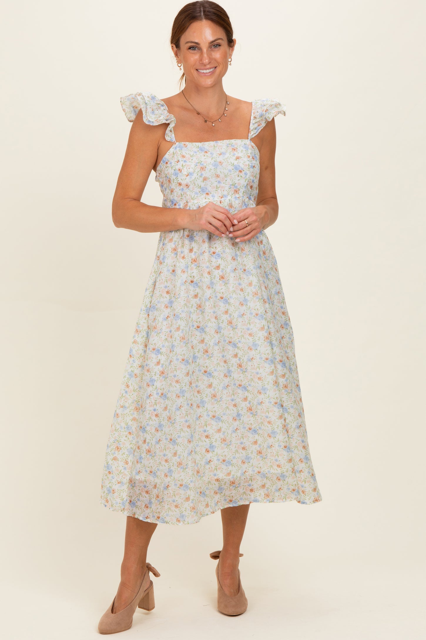 woman wearing a light blue floral midi dress with ruffle sleeves and nude heels