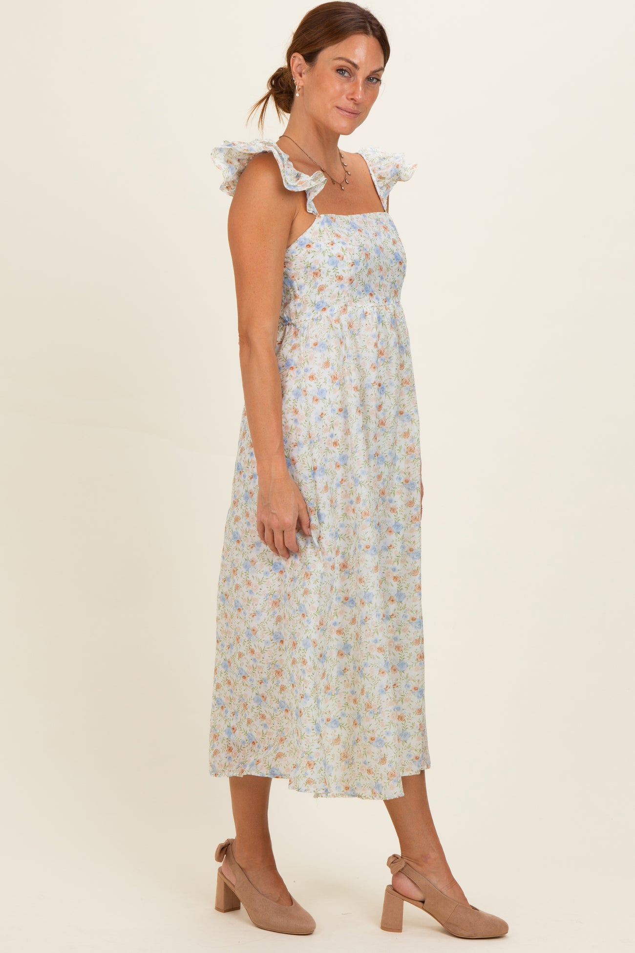 woman wearing a light blue floral maxi dress with ruffle straps and taupe block heel sandals