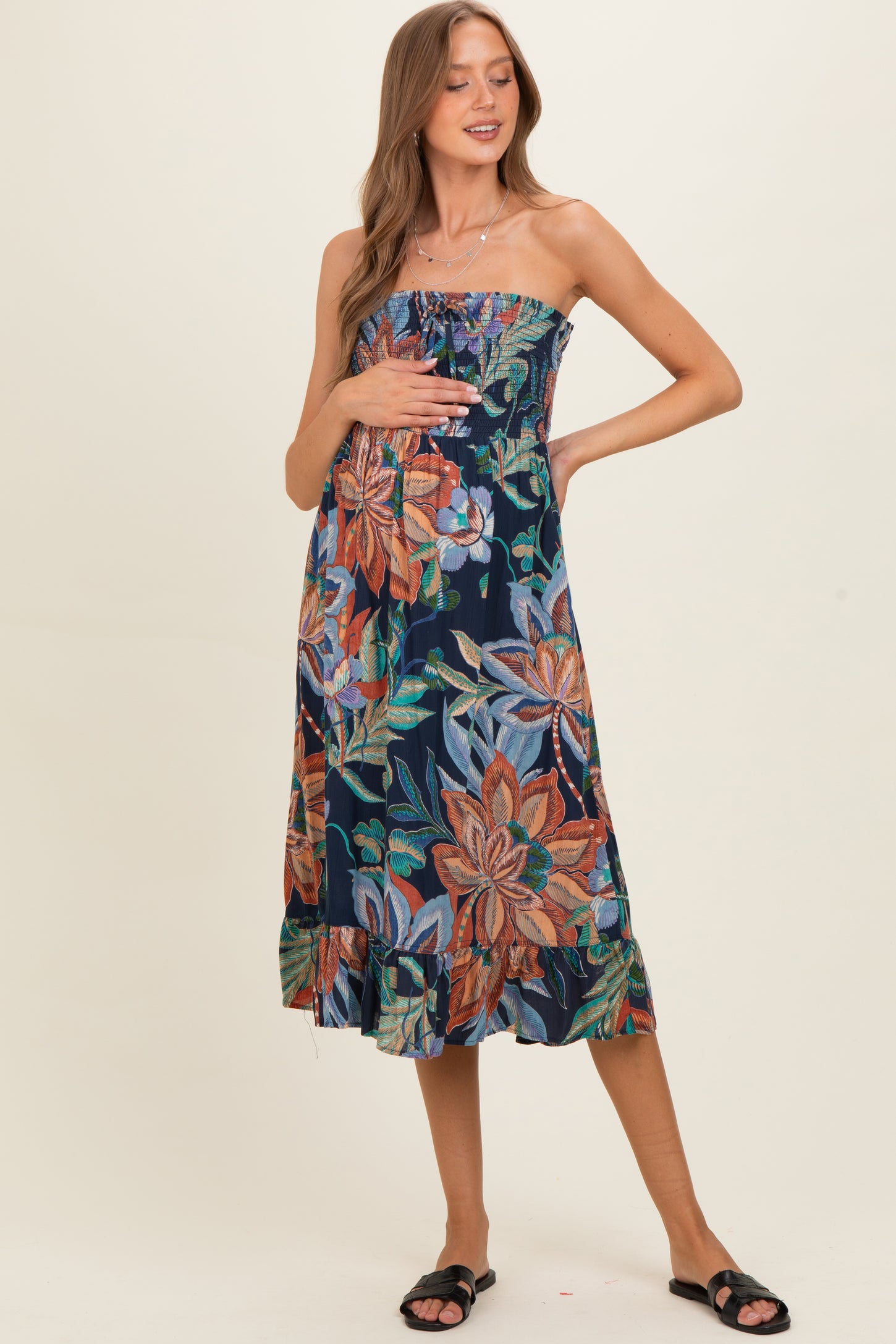 woman wearing a floral strapless maternity dress and gently holding her baby bump