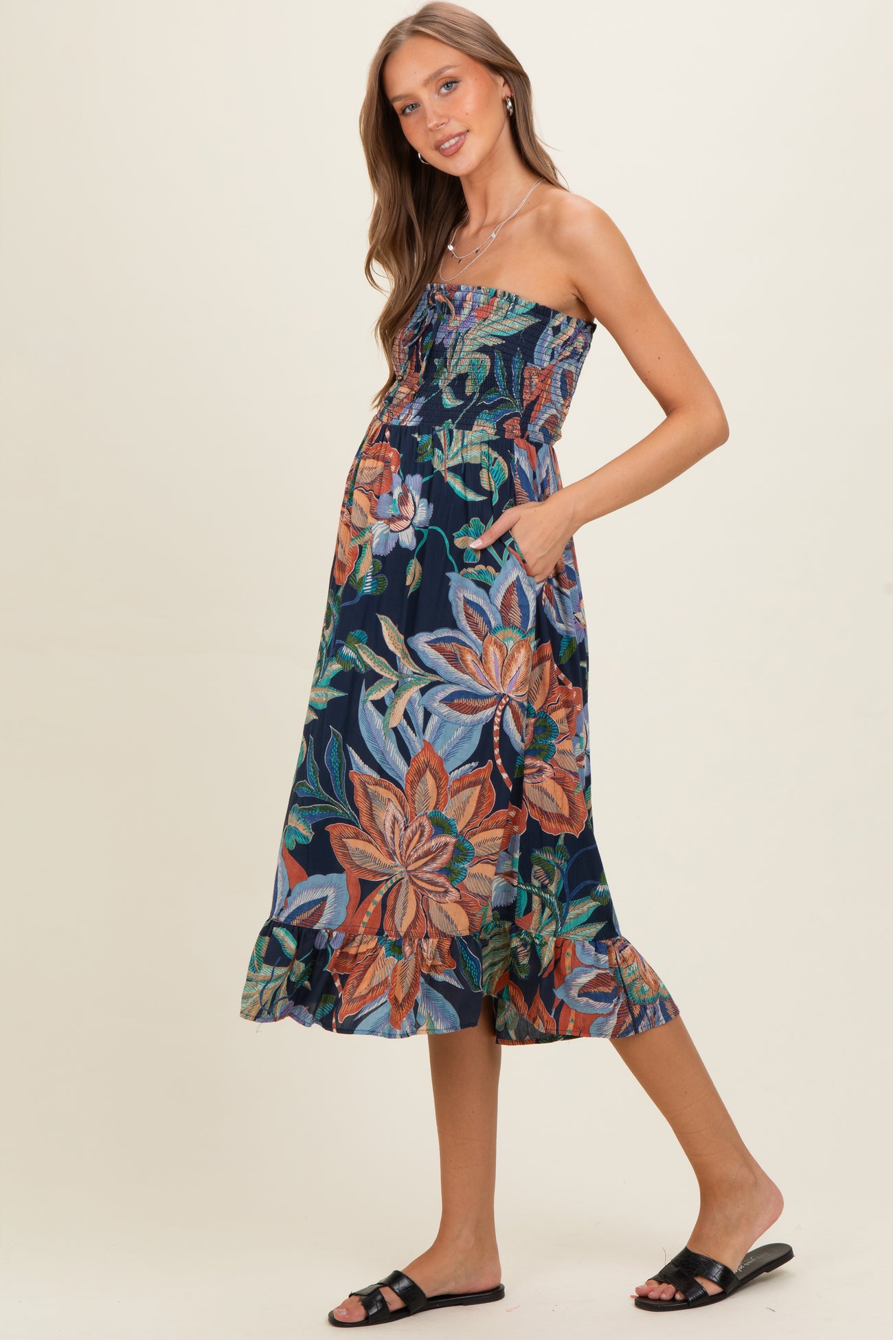 woman wearing a floral strapless maternity dress with pockets and a ruffled hem, showing her baby bump