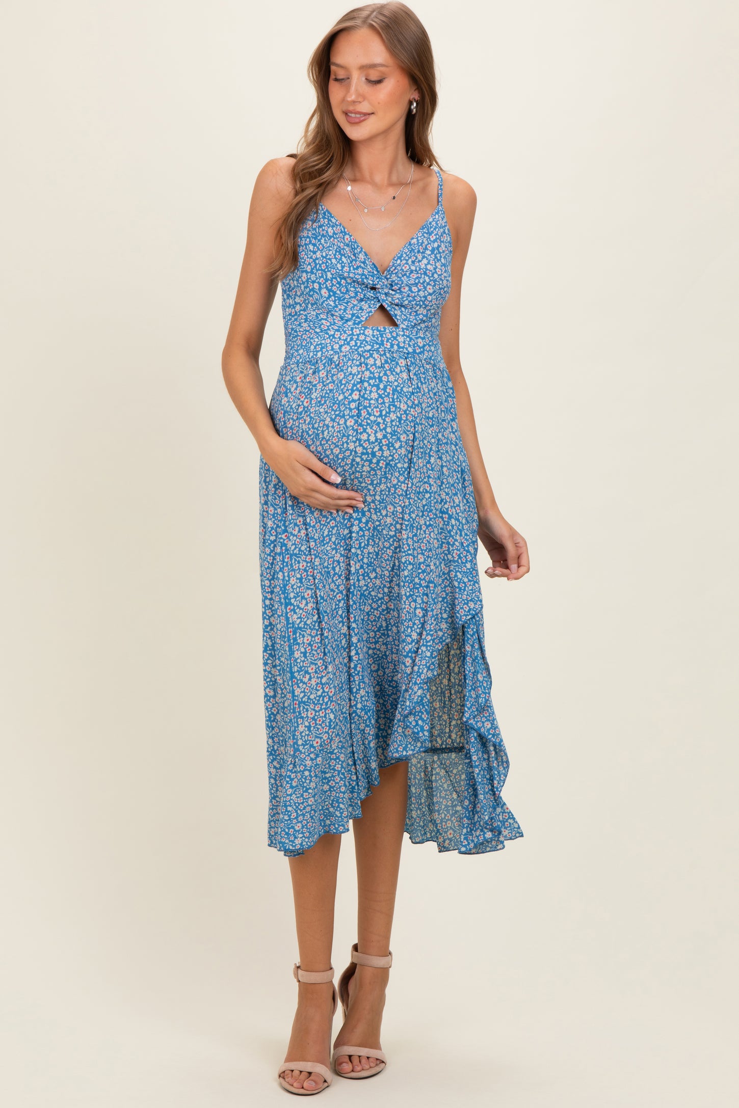 woman wearing a blue floral maternity dress with a knot detail, showing her baby bump and a flowing hemline