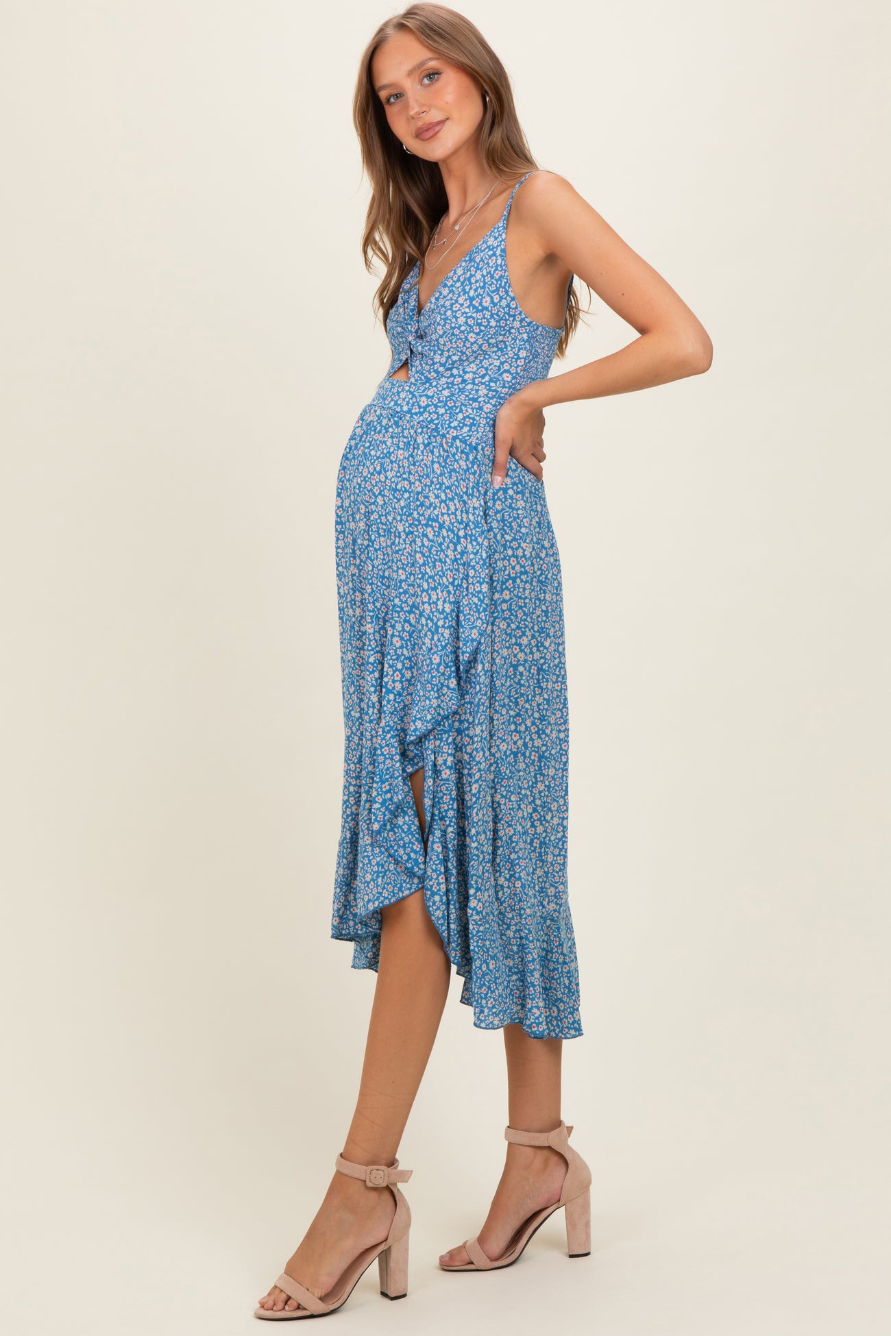 woman wearing a blue floral maternity dress with a v-neckline and ruffled hem, showcasing her baby bump