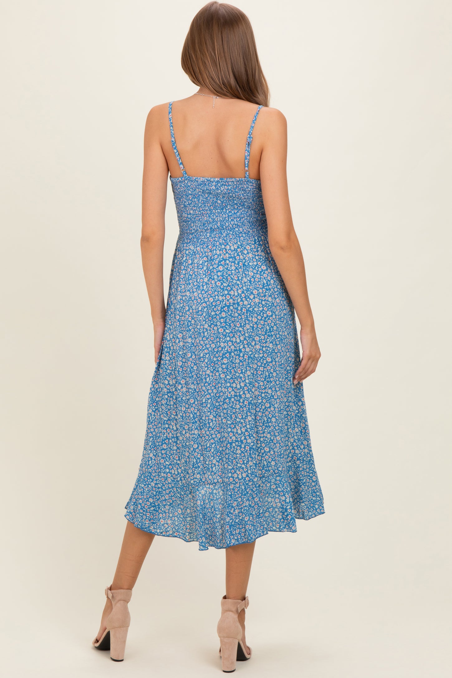 woman wearing a blue floral maternity dress with adjustable straps and a flowing skirt, showing a baby bump