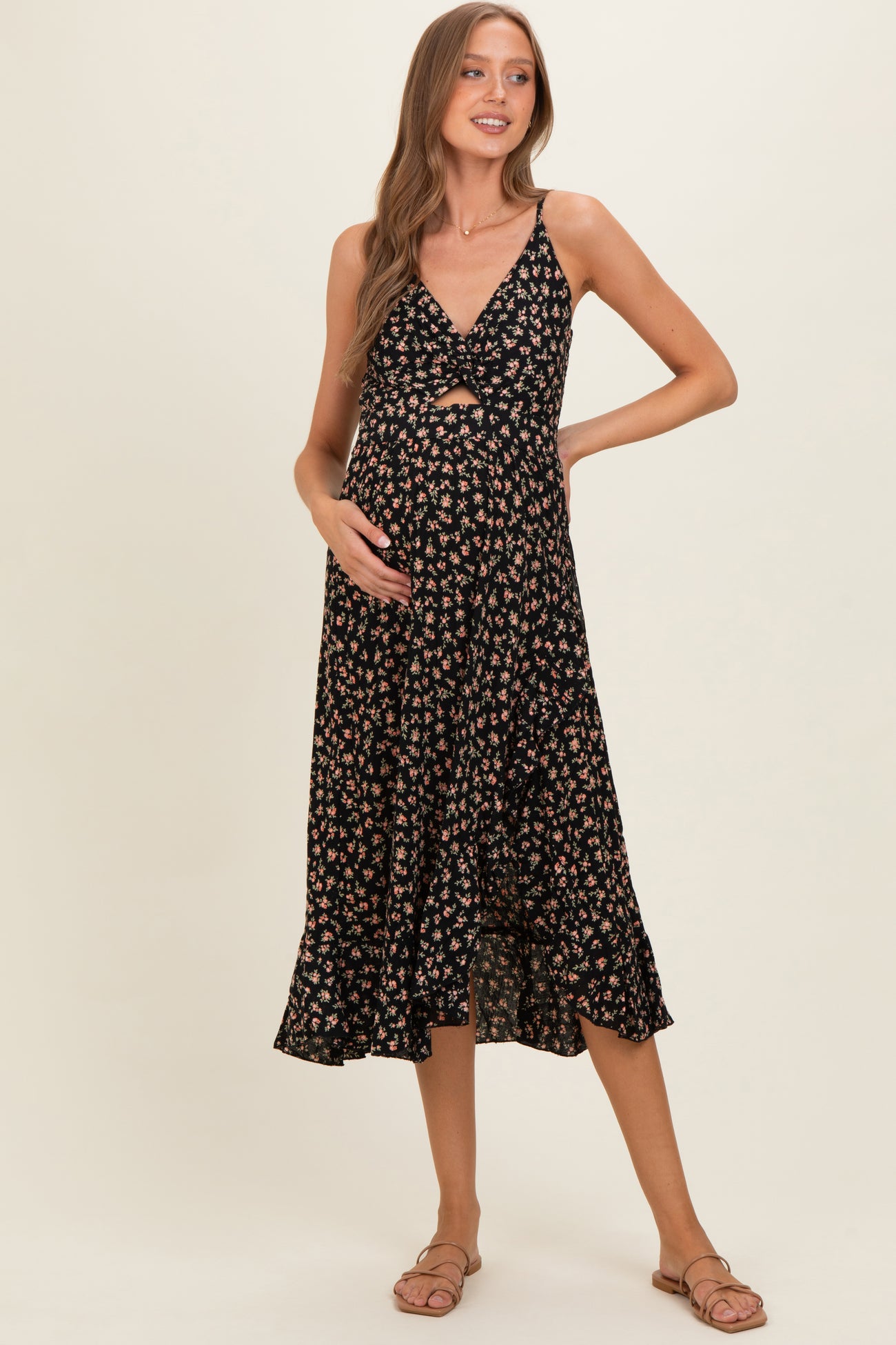 woman wearing a black floral maternity dress with a knot front detail and a flowy hem, highlighting her baby bump