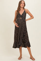 woman wearing a black floral maternity dress with a knot front detail and a flowy hem, highlighting her baby bump