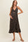 woman wearing a black floral maternity dress with a knot front detail and a flowy hem, highlighting her baby bump