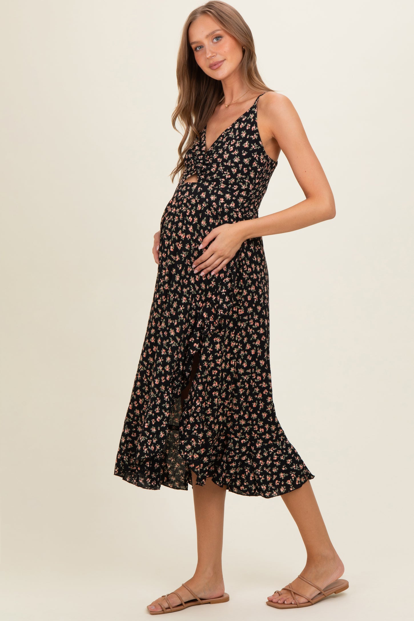 woman wearing a black floral maternity dress with a wrap design and holding her baby bump