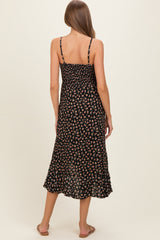woman wearing a black floral maternity dress with adjustable straps and a flowing hem