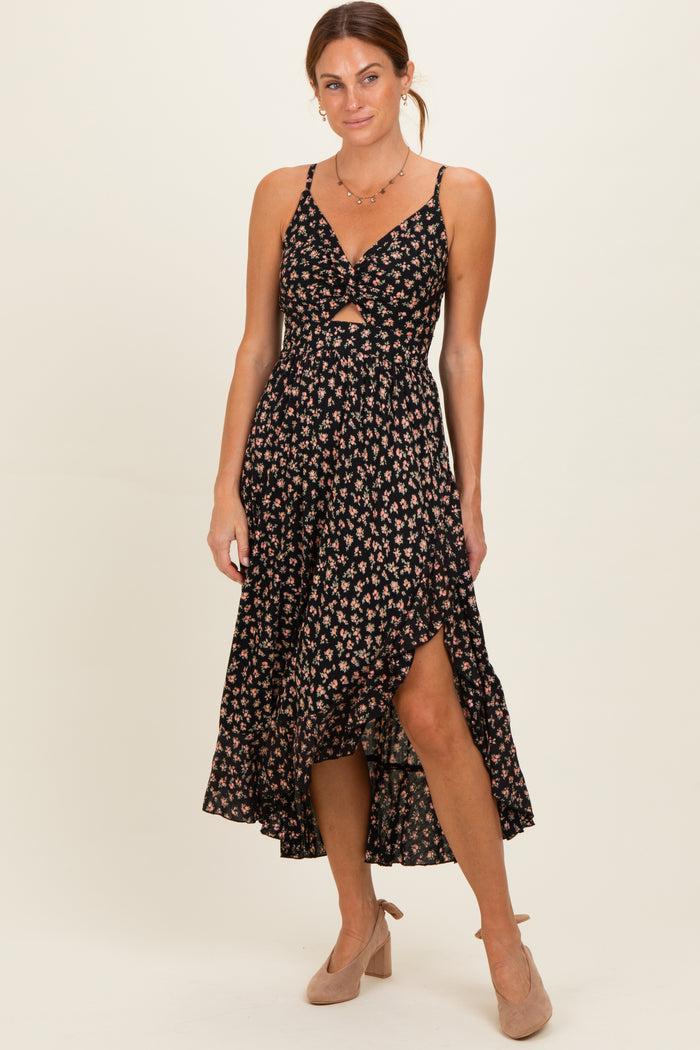 woman wearing a black floral midi dress with a front cutout and side slit, paired with nude heels