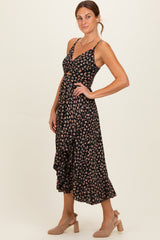 woman wearing a black floral midi dress with a cutout detail and ruffled hem, paired with beige block-heel shoes