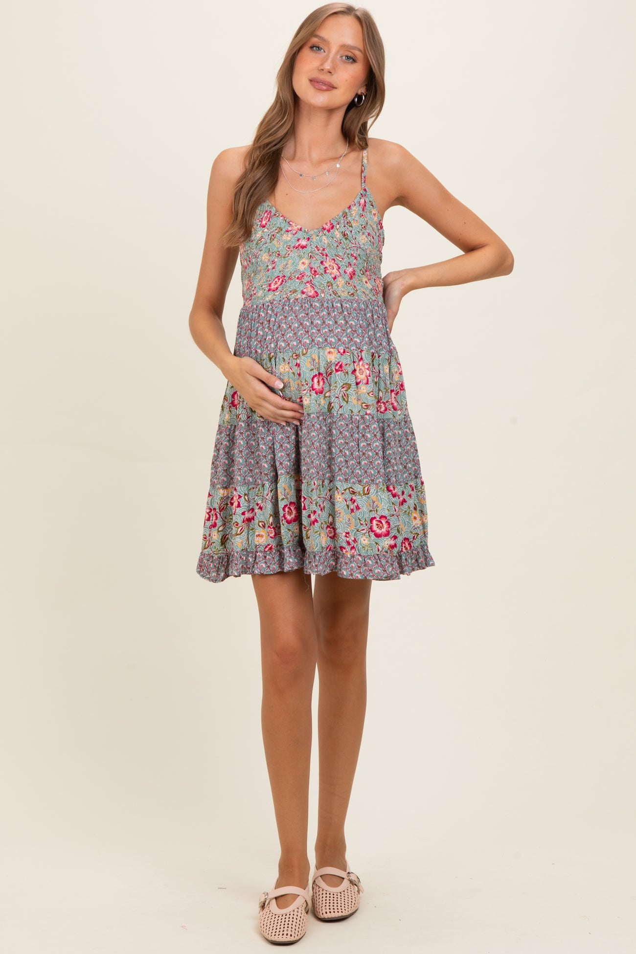 woman wearing a floral maternity dress with a fitted top and flared skirt, holding her baby bump
