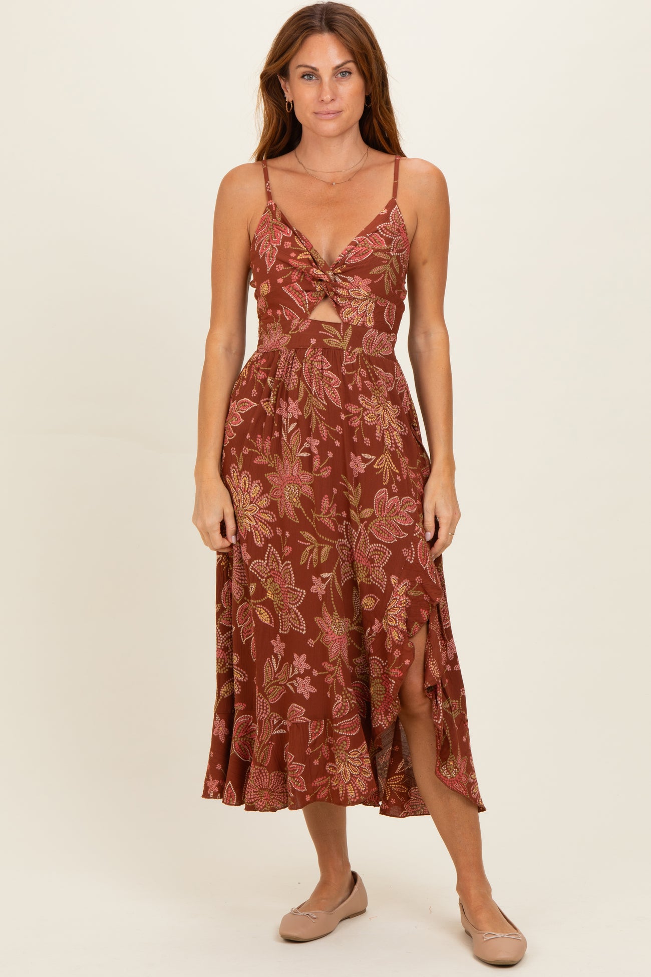 woman wearing a maroon floral midi dress with a knotted front and slits on the sides