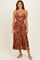 woman wearing a maroon floral midi dress with a knotted front and slits on the sides
