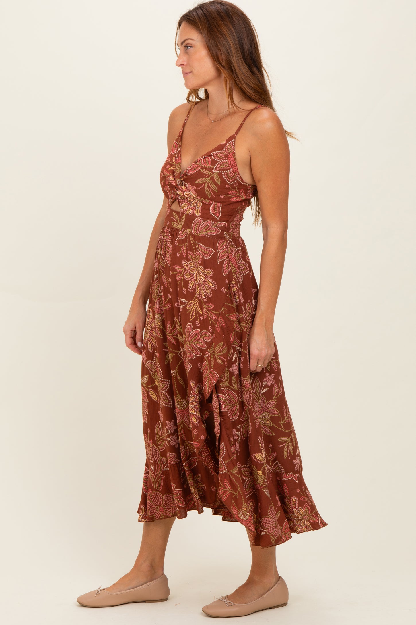 woman wearing a rust floral midi dress with spaghetti straps and a flared hem