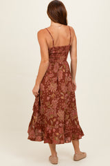woman wearing a spaghetti strap brown floral midi dress, showing a fitted bodice and flowing skirt from the back